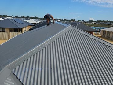 Person working on a metal rooftop under clear skies.