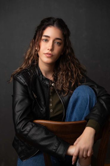 Young woman in leather jacket sitting on a chair.