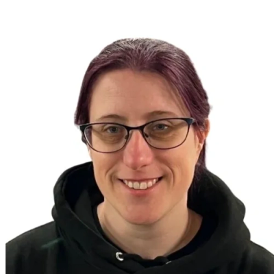 Smiling person with glasses and purple hair wearing a black hoodie.