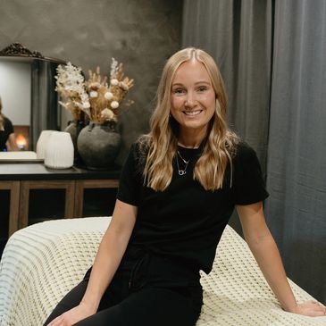 Smiling woman sitting on a bed in a cozy room.