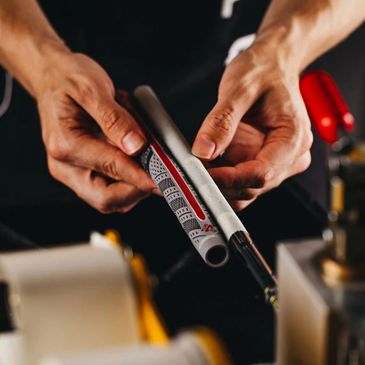 Hands inspecting a bicycle handlebar grip in a workshop.