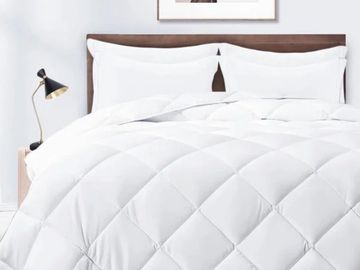 Cozy white quilted comforter on a neatly made bed with white pillows.
