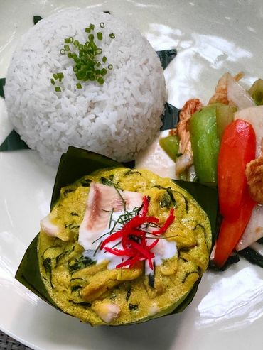 A plate of steamed rice, fish custard, and mixed vegetables with a bowl of rice.