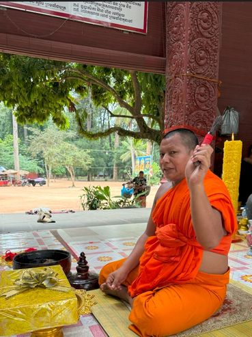 A monk in orange robes performing a ritual inside a temple.