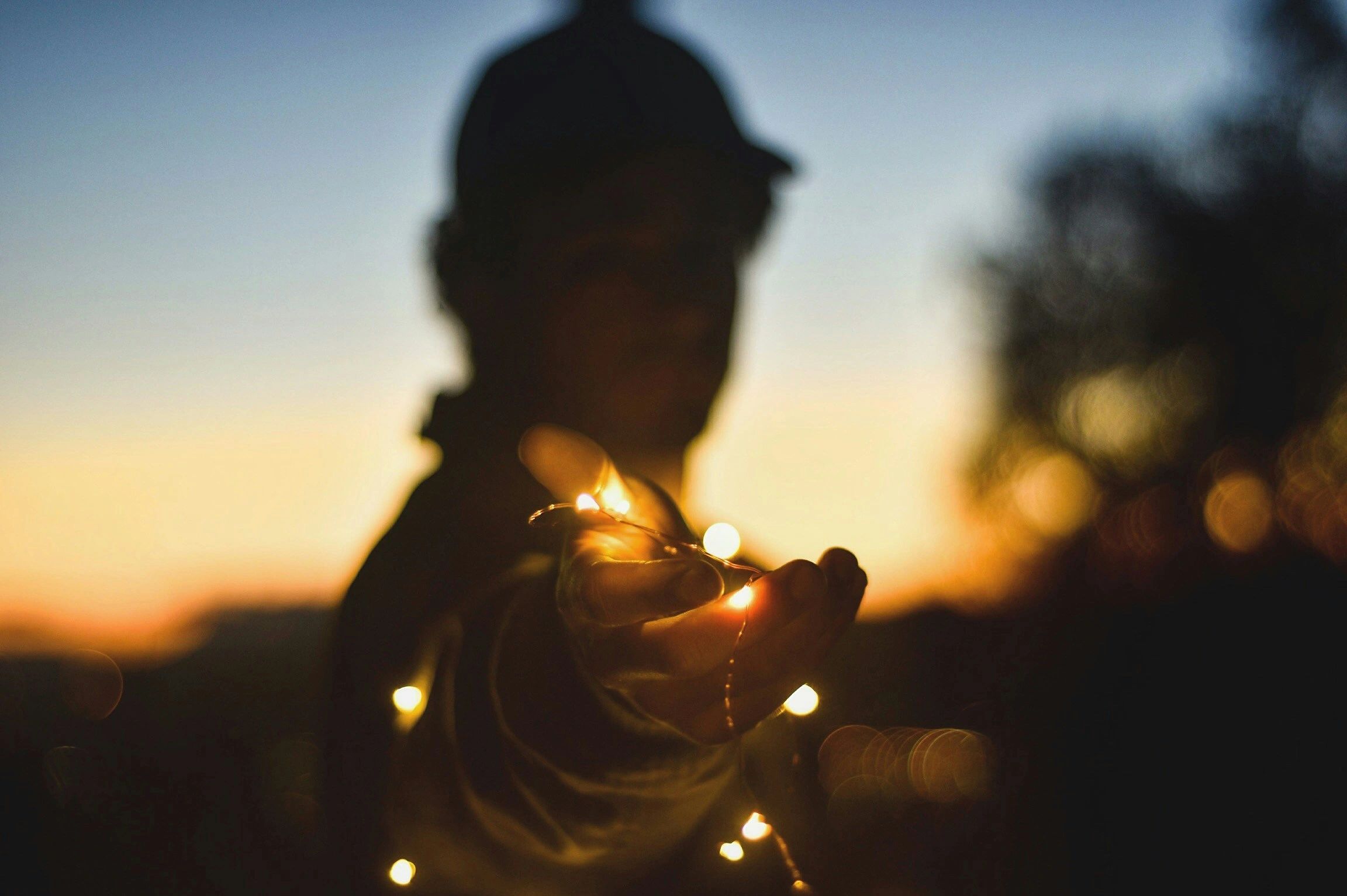 Image of a man in silhouette at sunset, extending a hand in invitation to join him.
