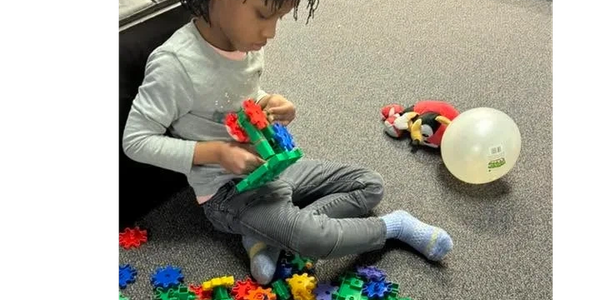 Child playing with colorful building blocks indoors.