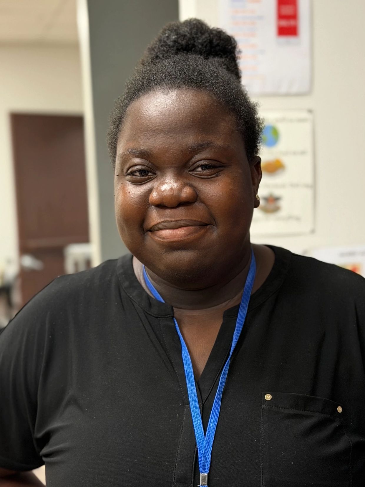 Smiling woman with a black shirt and blue lanyard.