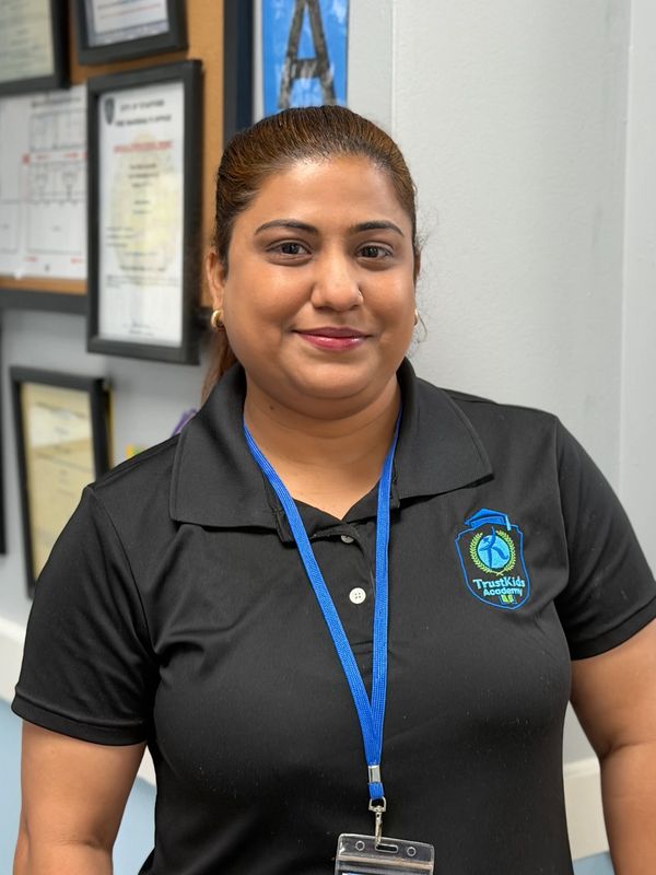 Smiling woman in black polo shirt with an ID badge.