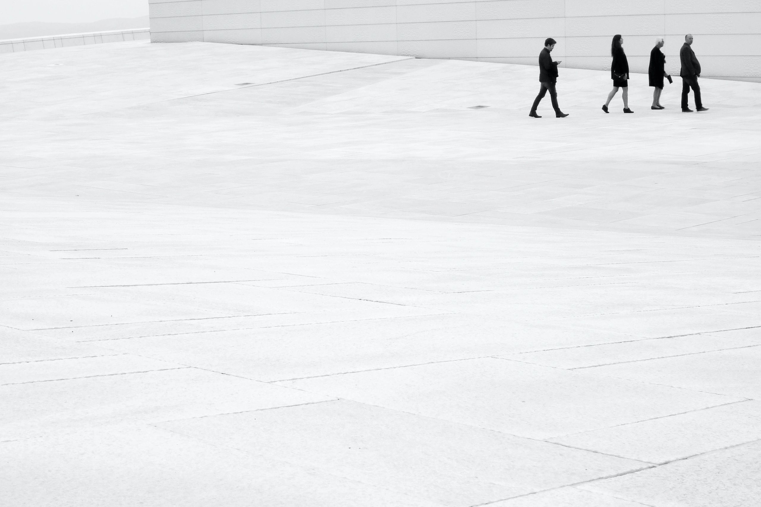 Black and white photo of four individuals walking after one another.