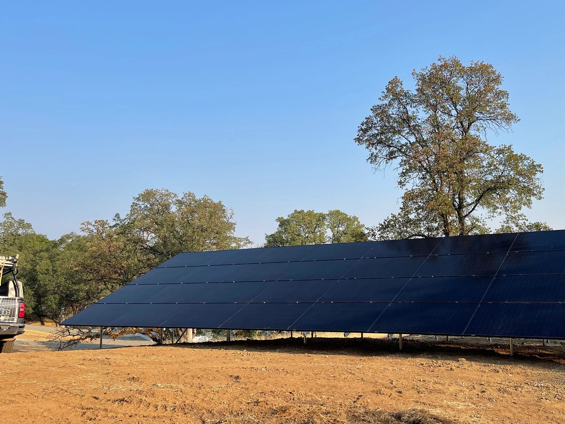 Solar panels installed in a sunny outdoor area with trees in the background.