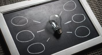 A lightbulb laying on a chalk board