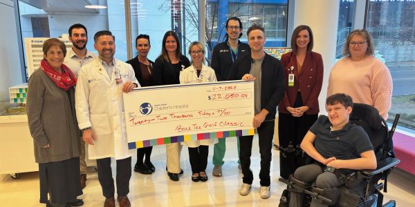Group holding a large check for $22,050.04 at a hospital.