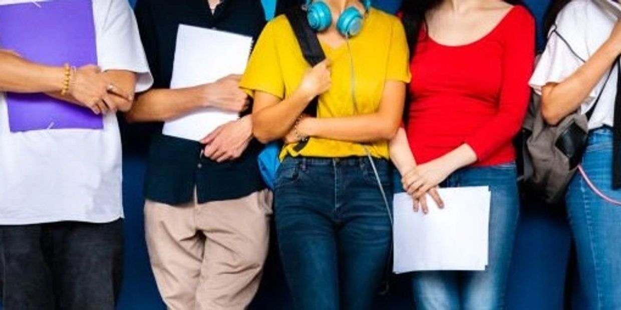 Group of students standing side by side holding notebooks and papers.