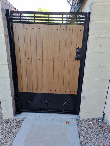 This custom gate features a heavy-duty steel frame paired with wood-style privacy panels for a moder