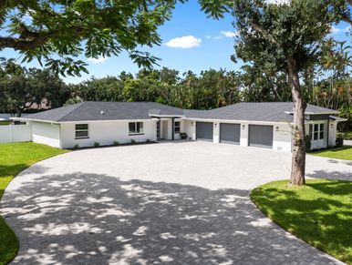 Modern one-story house with a large driveway and three-car garage.