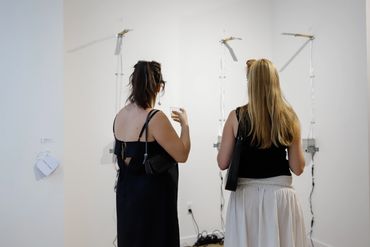 Two spectators looking at artwork during opening reception.