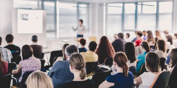 A classroom with students and a presenter teaching with the aid of a projected display