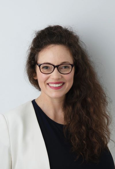 Smiling woman with glasses and curly hair.