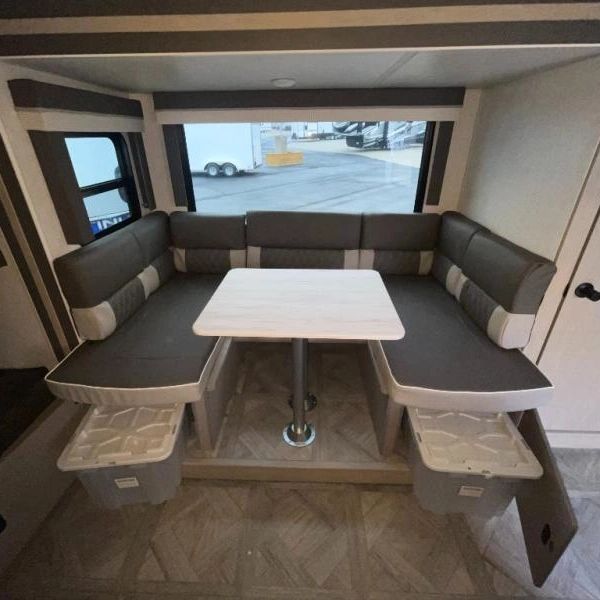 Close-up photo of the u-shaped dinette showing the large window views, as well as the storage areas.