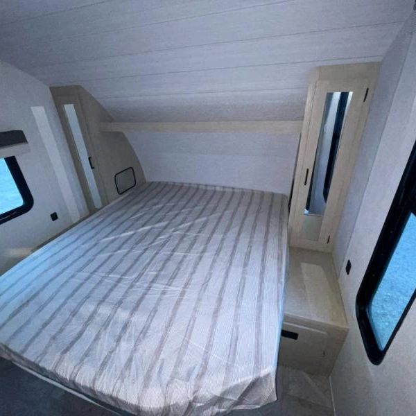 Photo showing bed with mirrored, hanging length cabinets on each side, as well as laundry chute.