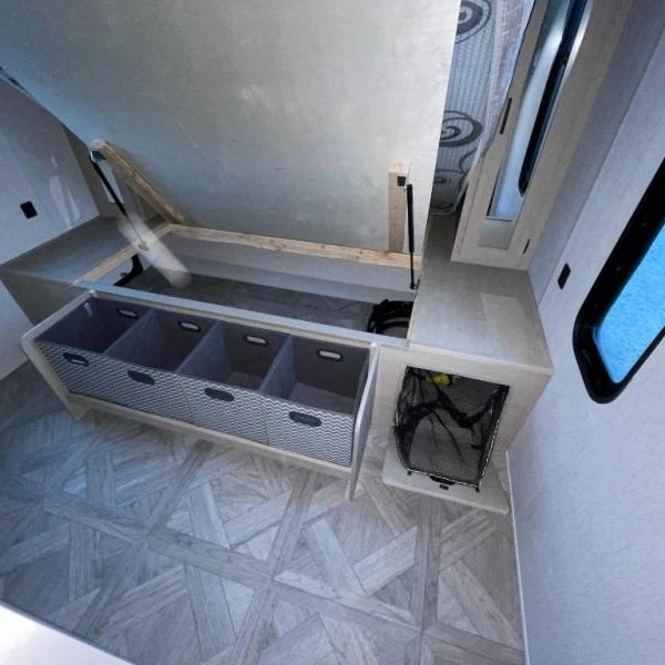 Photo showing bed in raised position for acess to large storage area, as well as fout storage totes