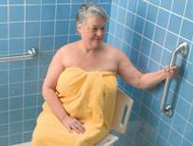 A woman holding grab bar inside the bathroom near toilets