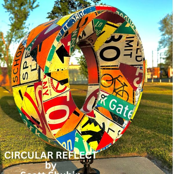 Colorful circular sculpture made from street signs in an outdoor park.