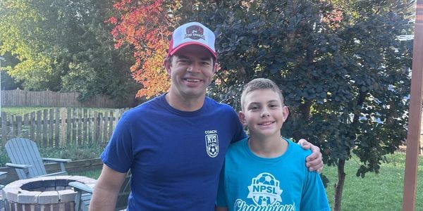 Eric in his Naperville Youth Soccer coach shirt with one of his players