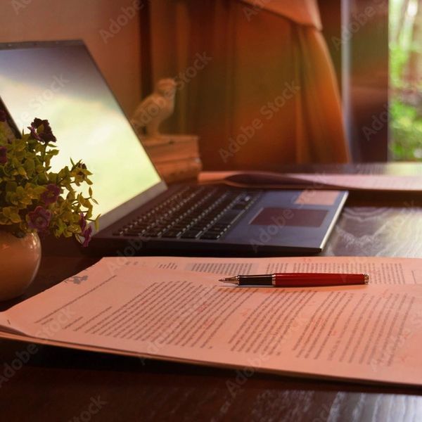 Ordinateur sur un bureau, feuillet avec stylo rouge.