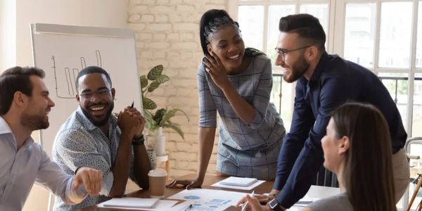 A diverse group of colleagues smiling and collaborating in a bright office meeting.