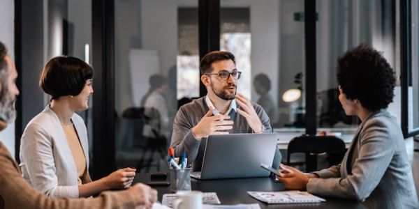 Business team discussing ideas around a laptop in a modern office.