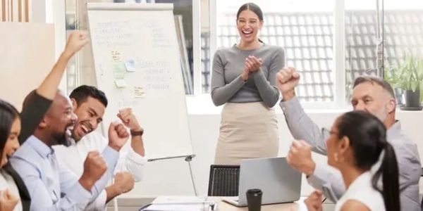 A joyful team celebrating success in a bright office meeting room.