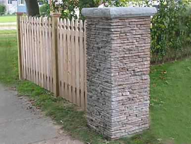 Stacked stone column with cap and wood slat fence attached. 