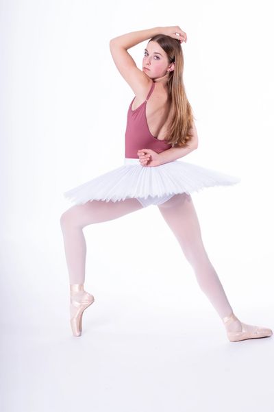 Ballerina in a white tutu and pink leotard poses.