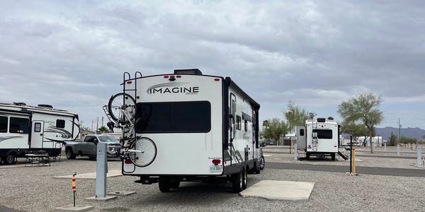 RVs parked on gravel lots under a cloudy sky at a campground.