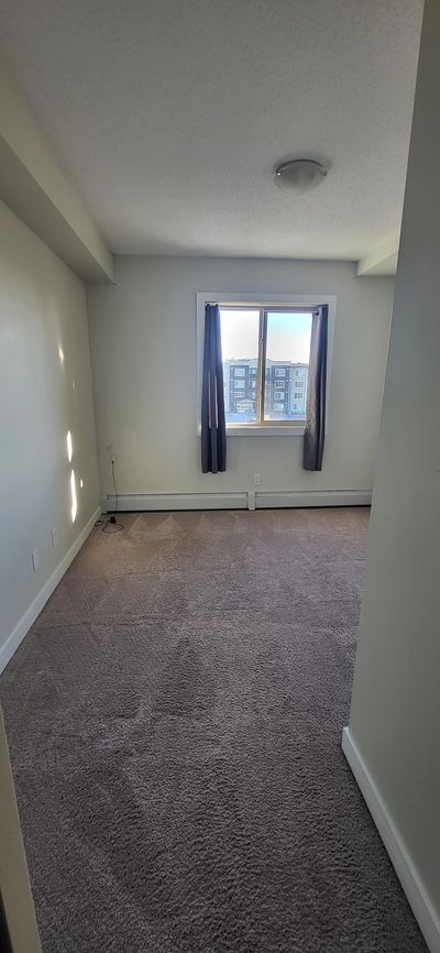 Empty room with carpeted floor and a window with curtains.