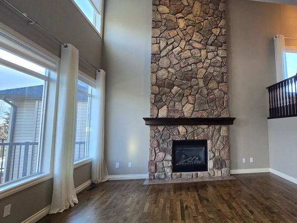 Spacious living room with a tall stone fireplace and large windows.