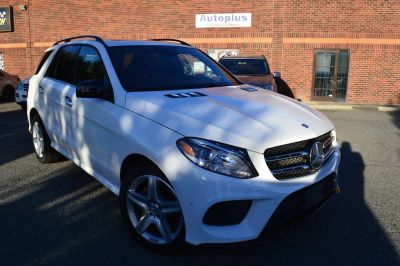 White Mercedes-Benz SUV parked outside a brick building.