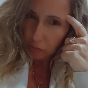 Close-up portrait of a woman with wavy hair and a ring on her finger.