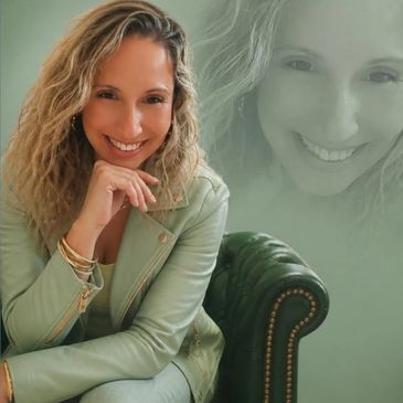 A smiling woman with curly hair in a light green jacket.