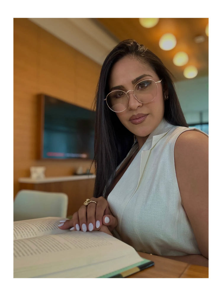 Woman with glasses reading a book in a modern room.
