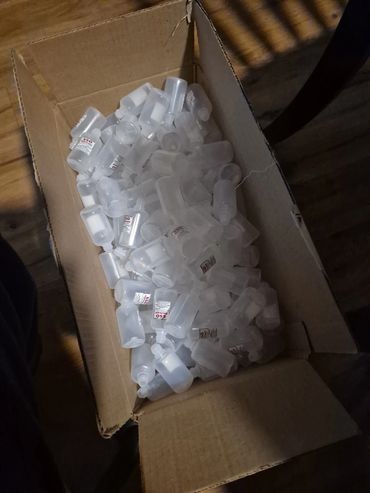 Cardboard box filled with empty small plastic bottles labeled 'SSO lubricant'.