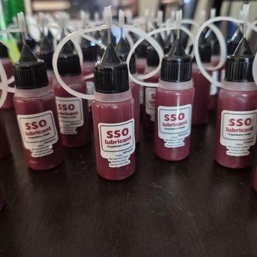 Multiple bottles of SSO lubricant with black caps and labels on a dark surface.