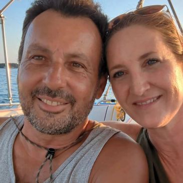 A happy couple taking a selfie on a boat during sunset.