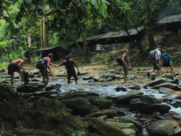 Group of people crossing the river to the campsite in the jungle of Bukit Lawang