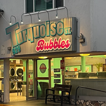 Exterior view of Turquoise Street Bubbles laundromat at dusk.