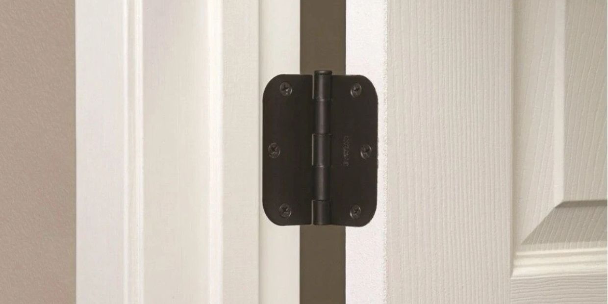 Close-up of a black door hinge on a white door frame.