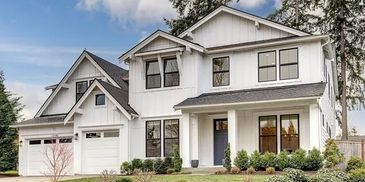 Modern two-story white house with a landscaped front yard and double garage.
