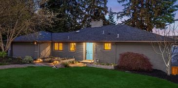 Cozy single-story home with blue door and lit windows at dusk.