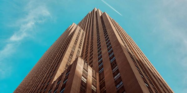 Looking up at a tall skyscraper against a bright blue sky.